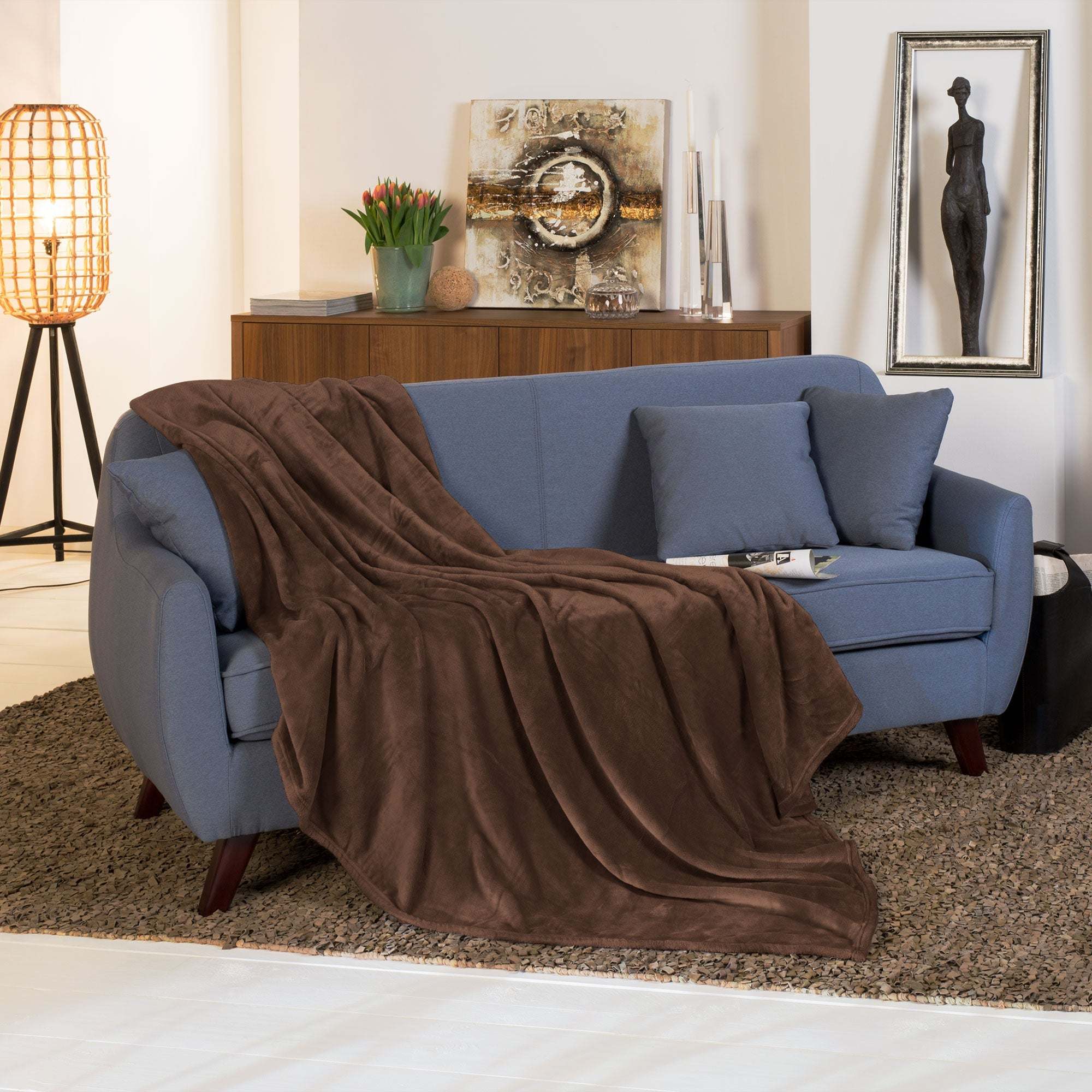 Beautissu XXL Tagesdecke Kuscheldecke Aurelia draped over a blue sofa in a cozy living room.
