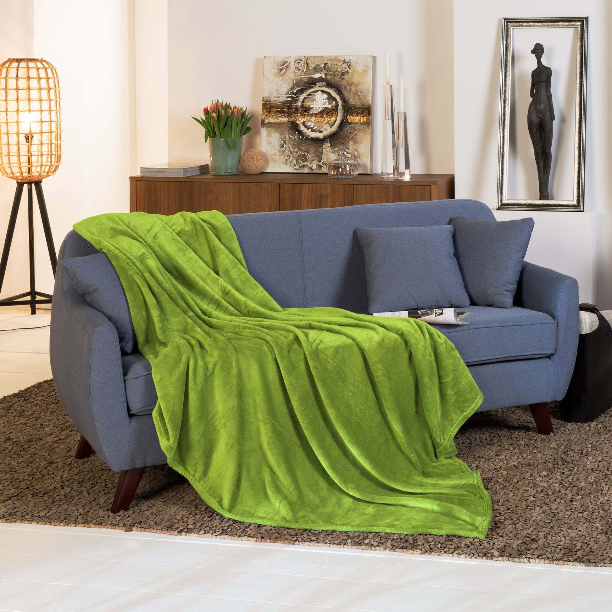 Beautissu XL Tagesdecke Kuscheldecke Aurelia 150x200cm in elegantem grün auf Sofa drapiert.