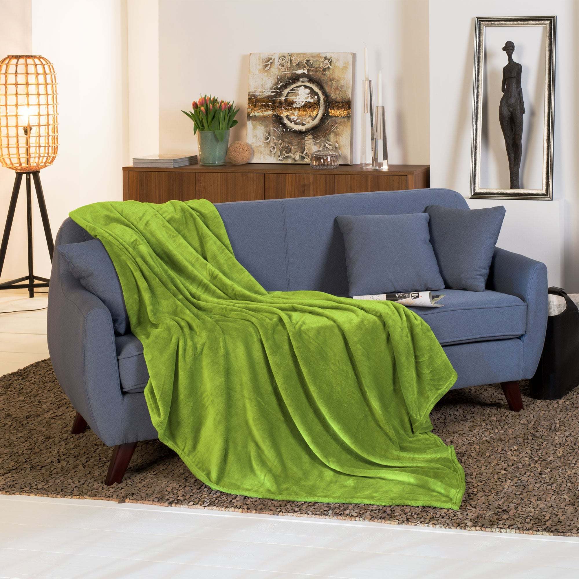 Beautissu XL Tagesdecke Kuscheldecke Aurelia 150x200cm in elegantem grün auf Sofa drapiert.