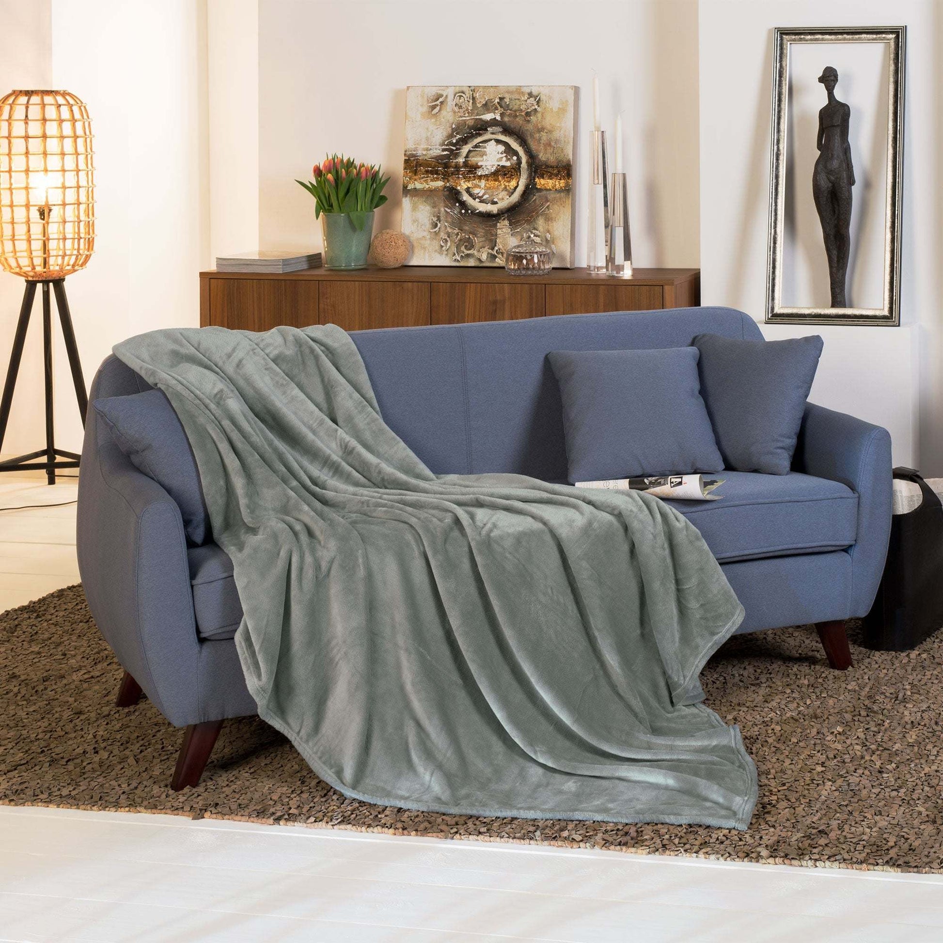 Beautissu XXL Tagesdecke Kuscheldecke Aurelia 220x240cm in elegantem Wohnraum auf Sofa drapiert.