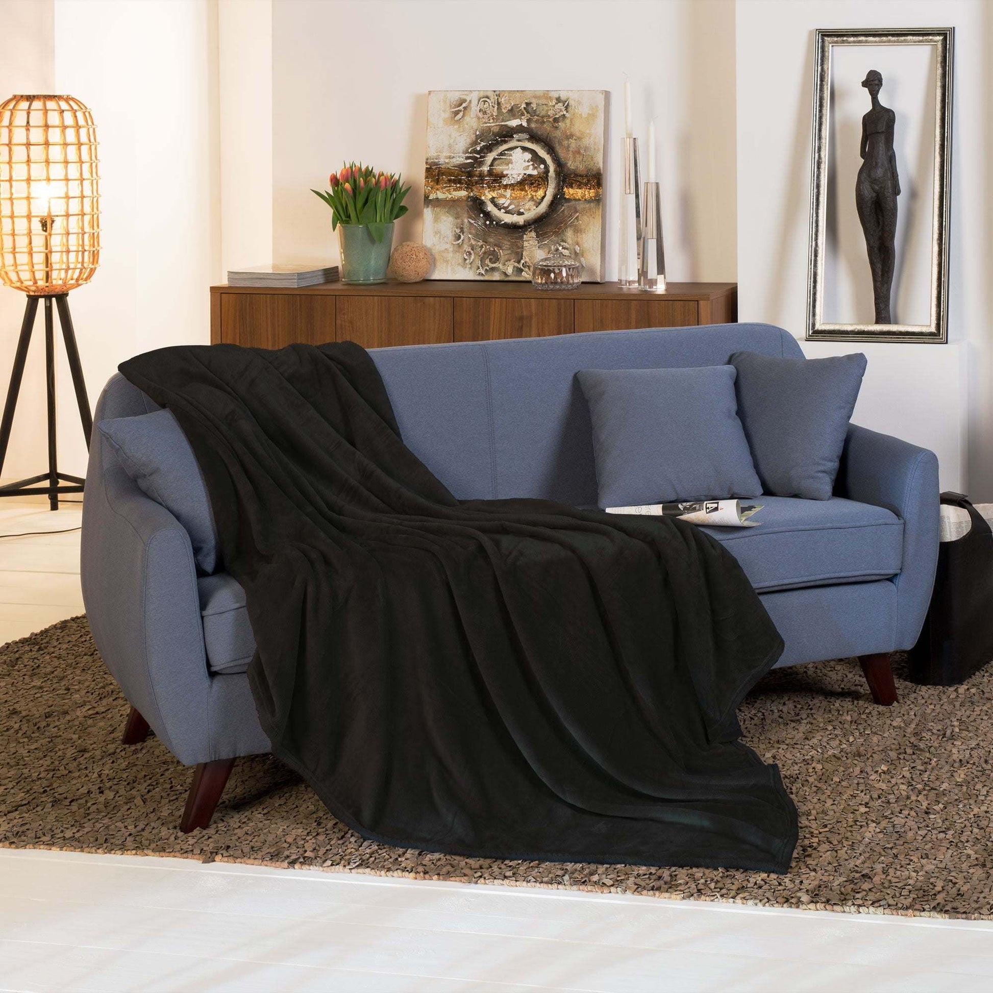 Beautissu XL Tagesdecke Kuscheldecke Aurelia 150x200cm draped over a blue sofa in a cozy living room.