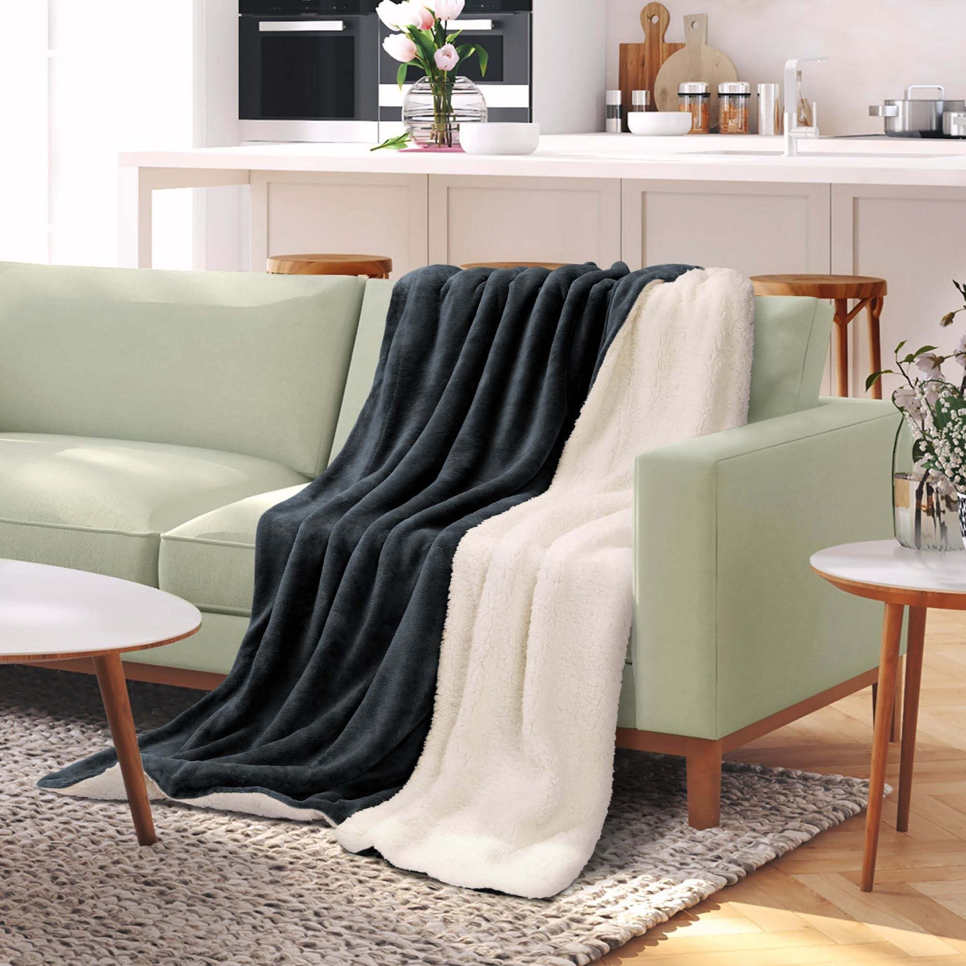 Beautissu Sherpa Kuscheldecke Alina in gray and white on green sofa, sizes 150x200cm/220x240cm, cozy and warm polyester.