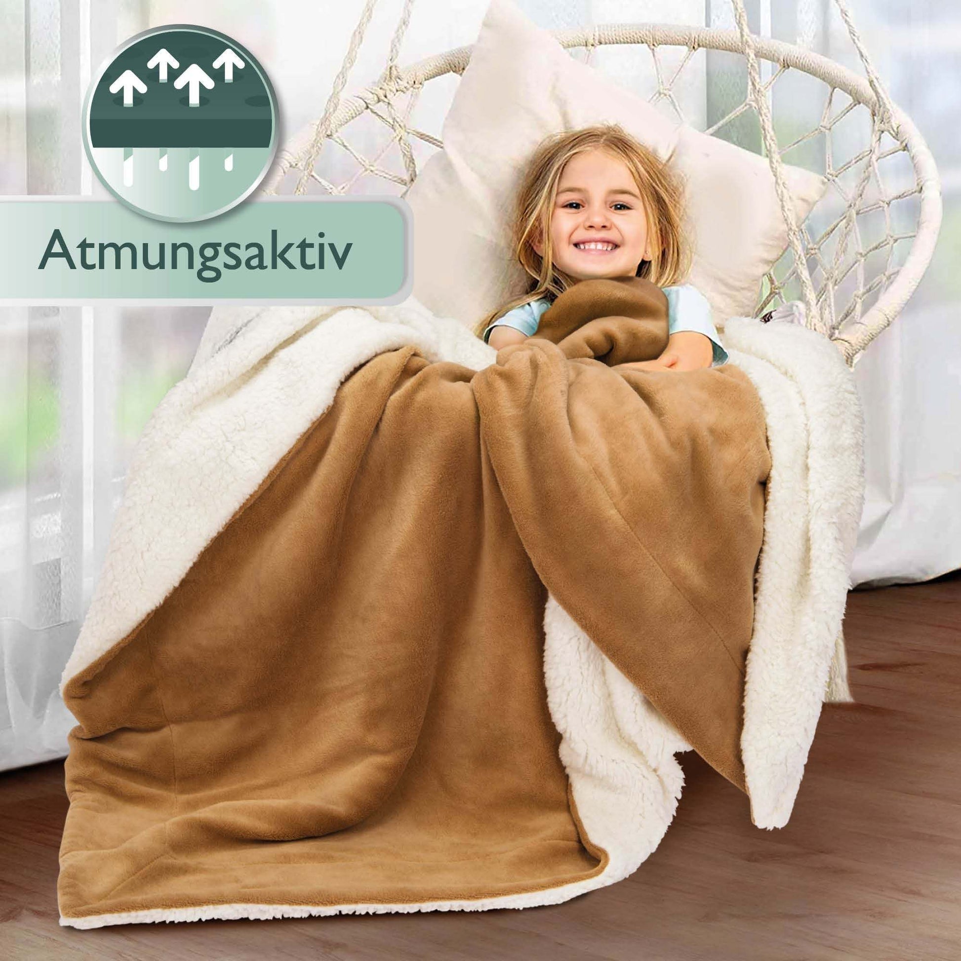 Beautissu Sherpa Kuscheldecke Alina in beige covering a child on a chair, 150x200cm/220x240cm sizes, soft microfibre polyester, warm and breathable.