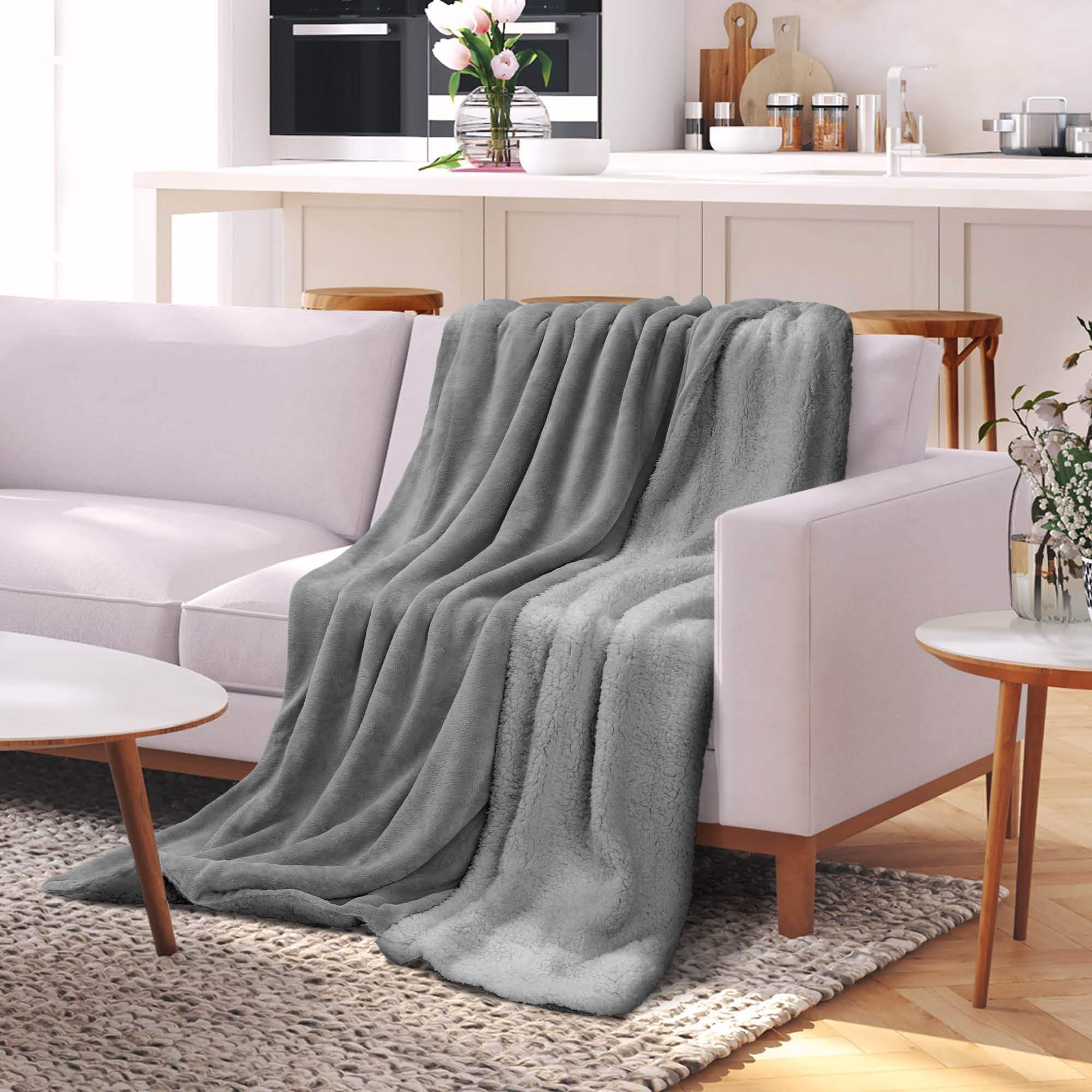 Beautissu Sherpa Kuscheldecke Alina in Grau auf einem Sofa, erhältlich in Größen 150x200cm oder 220x240cm.