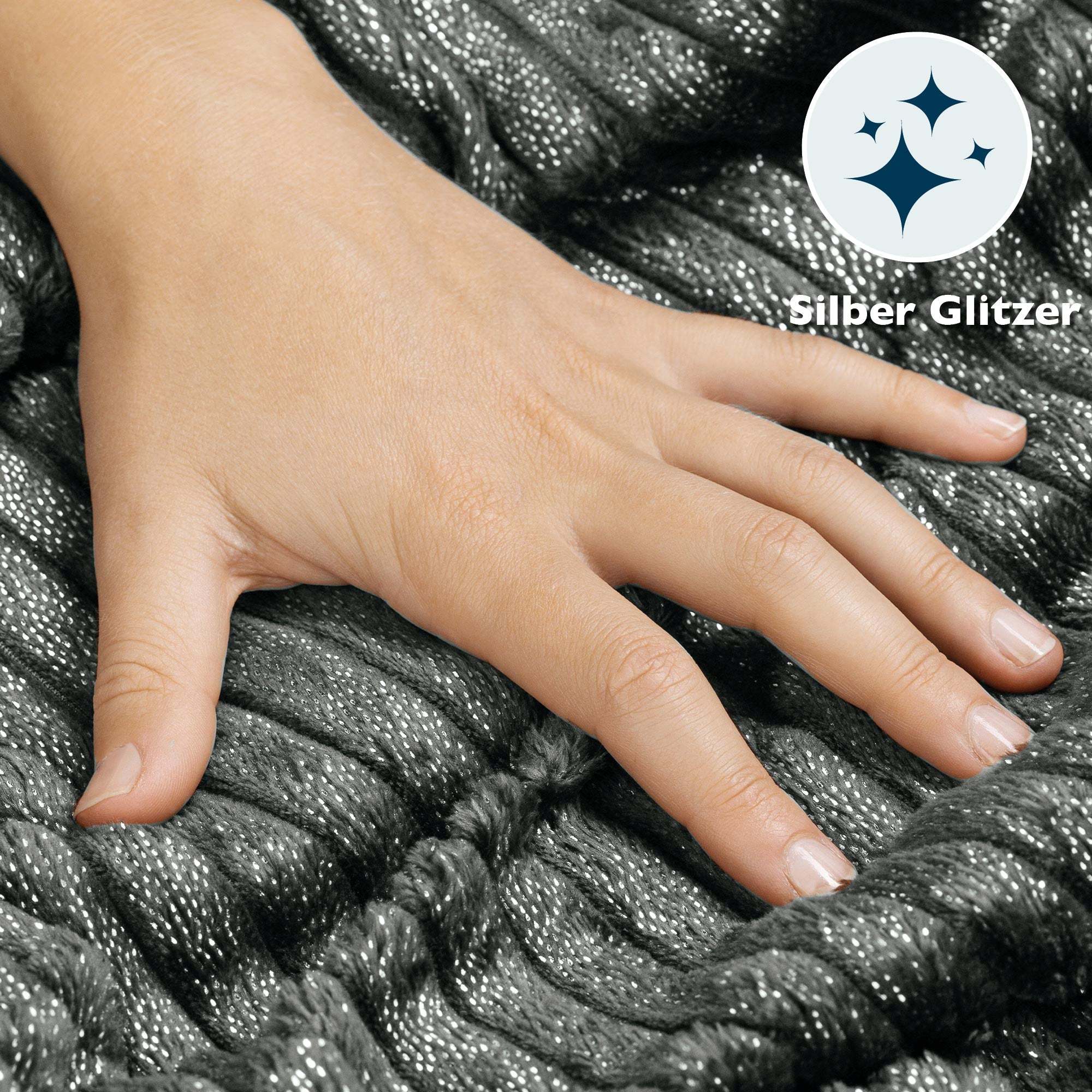 Hand touching gray, fluffy Beautissu Sherpa blanket with silver glitter pattern.