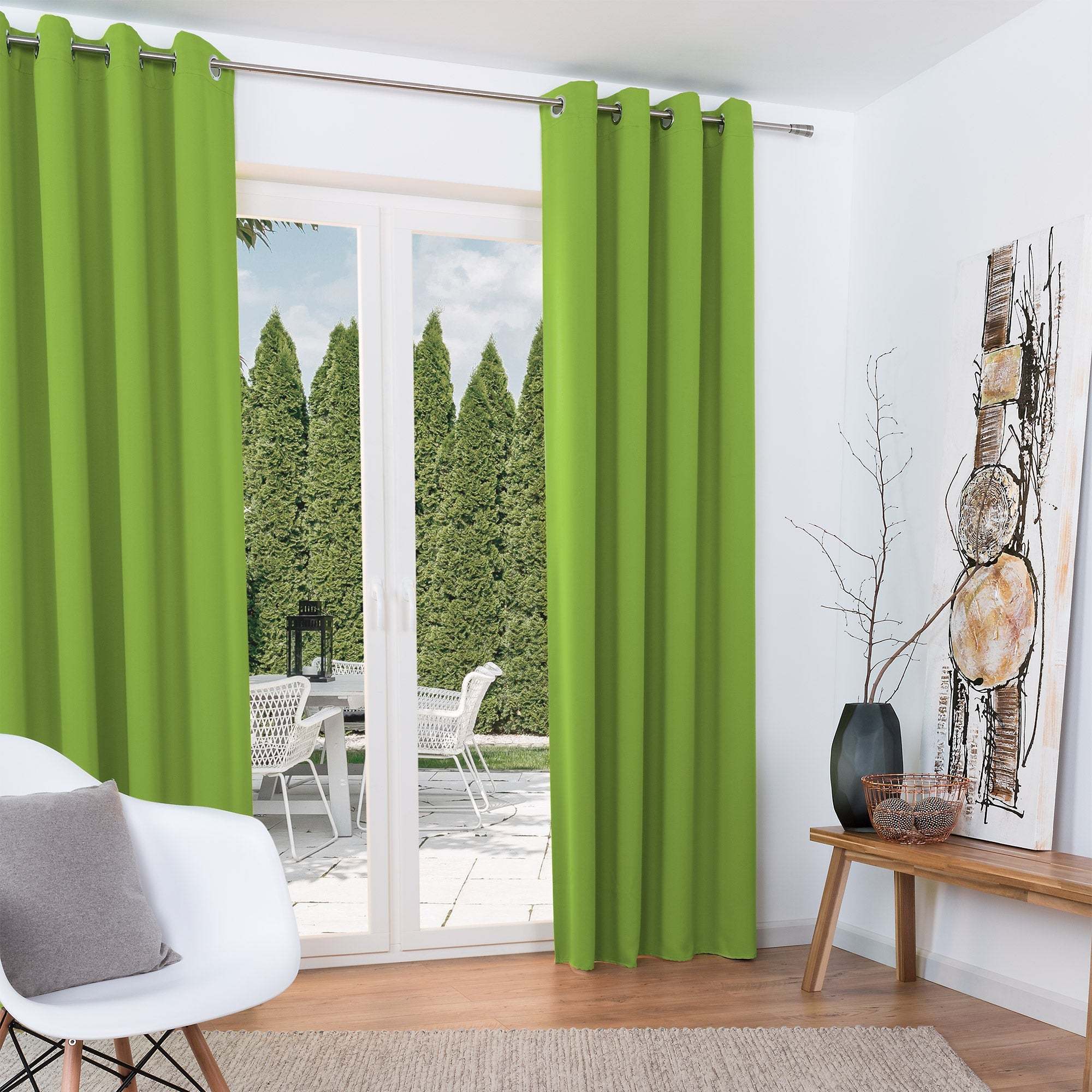 Green Beautissu Ösenschal Amelie blackout curtains in a bright living room setting.