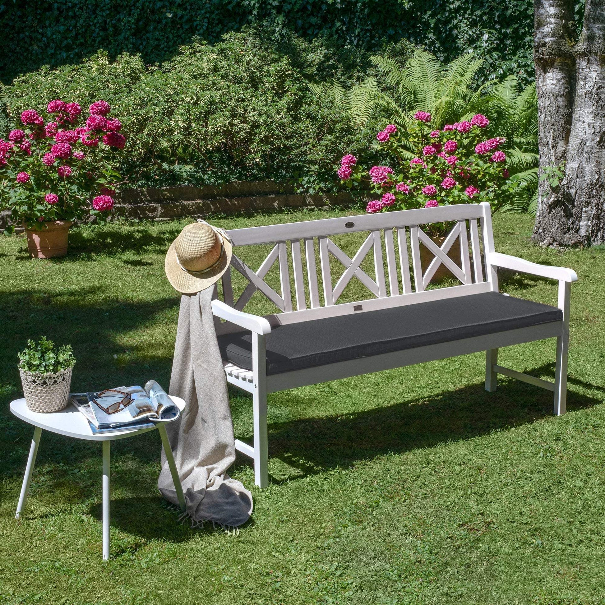 Beautissu Base BK bench cushion in a garden setting with vibrant flowers and greenery.