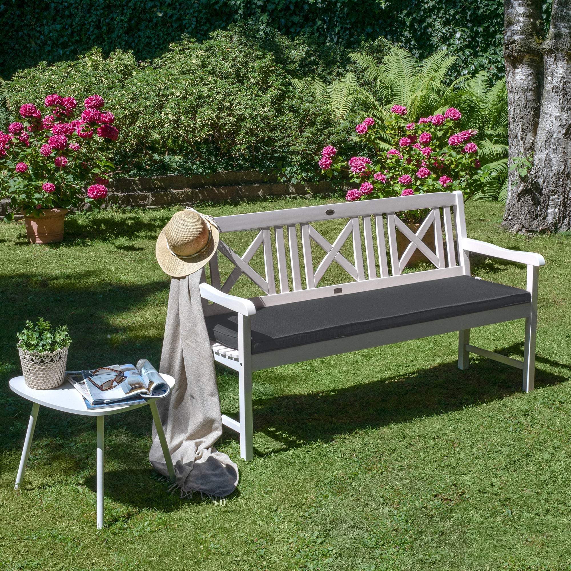 Beautissu Base BK bench cushion in a garden setting with vibrant flowers and greenery.