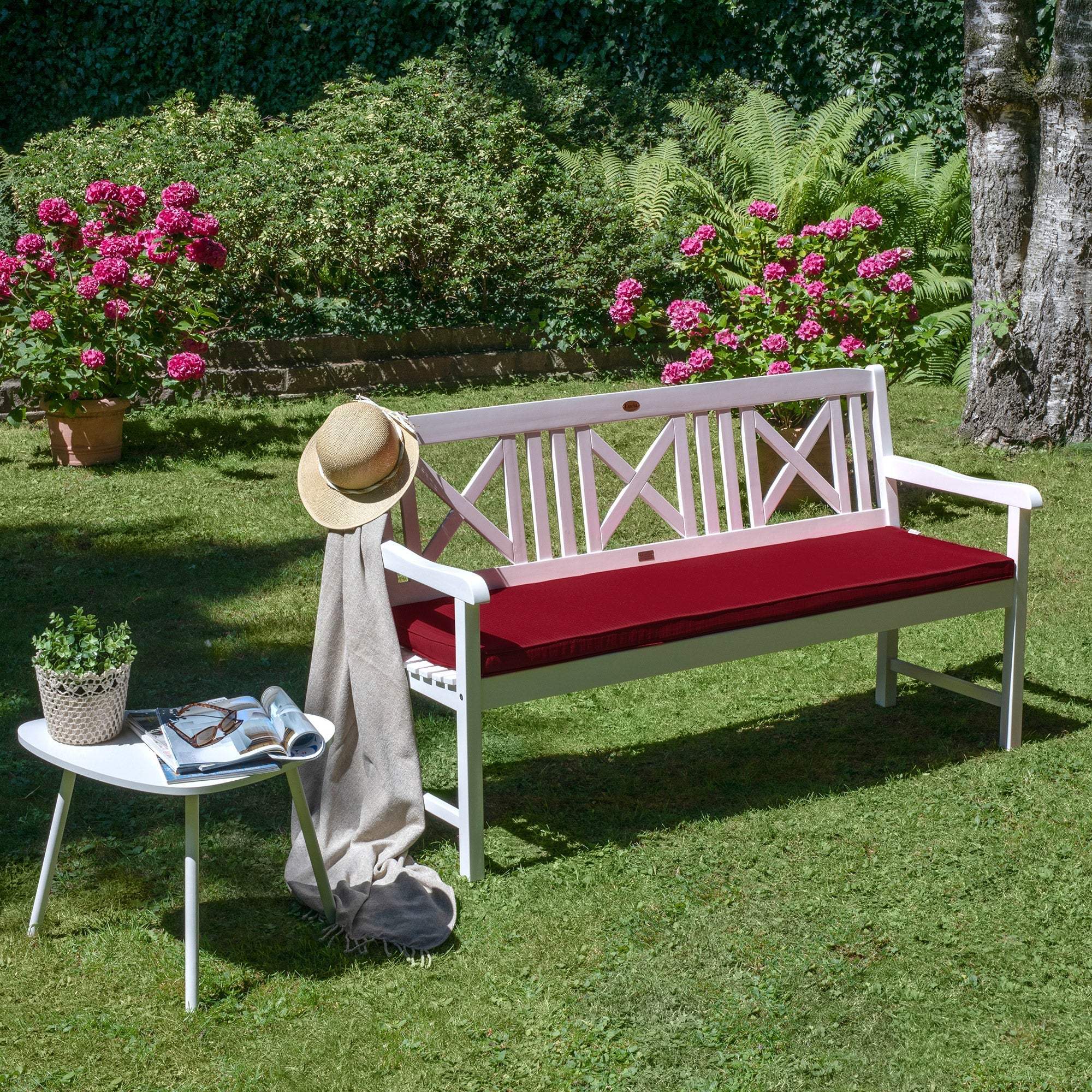 Beautissu Base BK seat cushion on garden bench with red cover in outdoor setting.