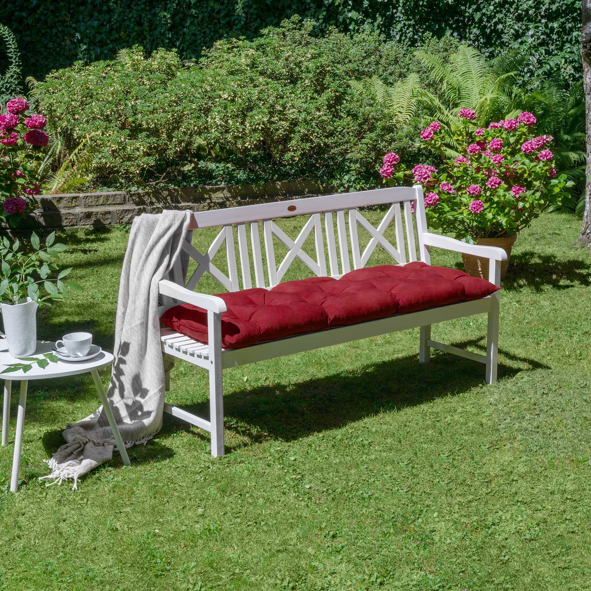 Beautissu Bankauflagen Flair BK cushion on white garden bench with vibrant red color and cozy design in a lush garden setting.