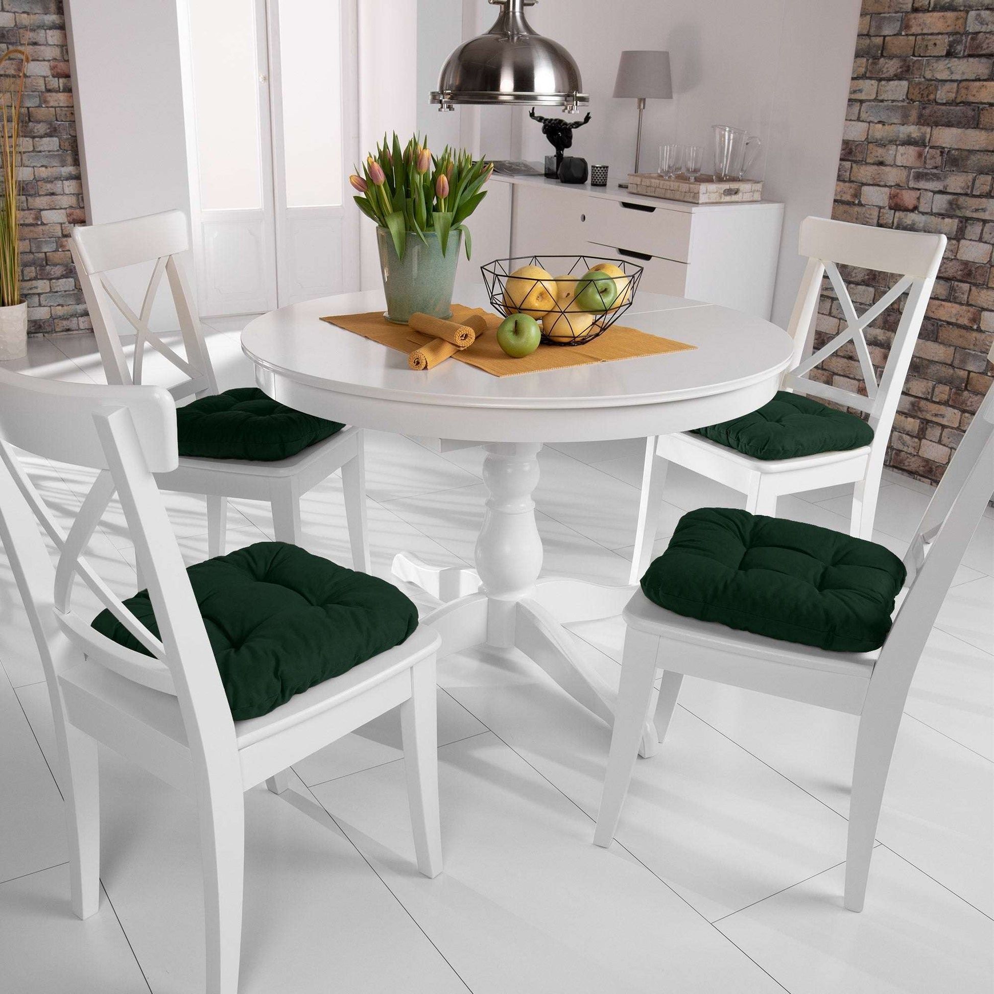 4-piece Beautissu Lisa chair cushion set in green on white dining chairs around a wooden table in a modern kitchen.