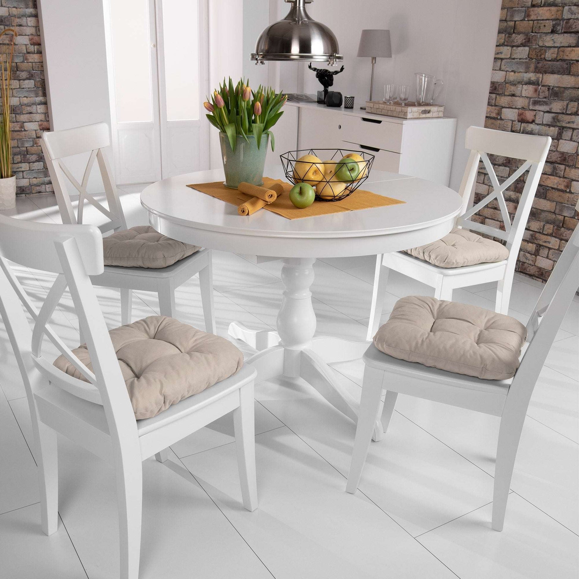 4-piece set of Beautissu Lisa chair cushions in beige on white wooden chairs around dining table.